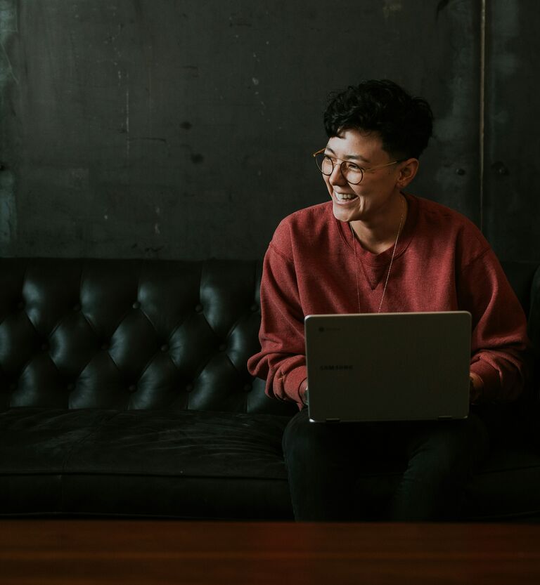Person am Laptop auf einem Sofa